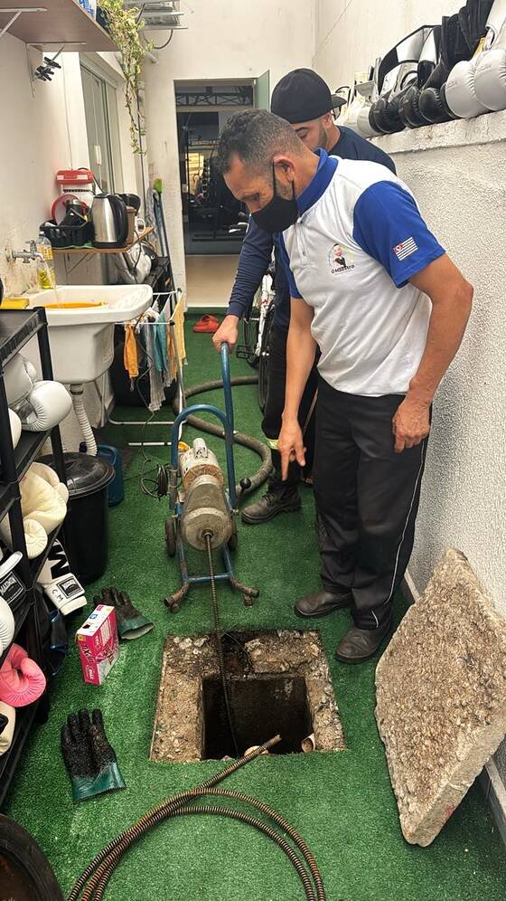 Técnicos do O Maestro desentupindo caixa de esgoto com máquina rotativa